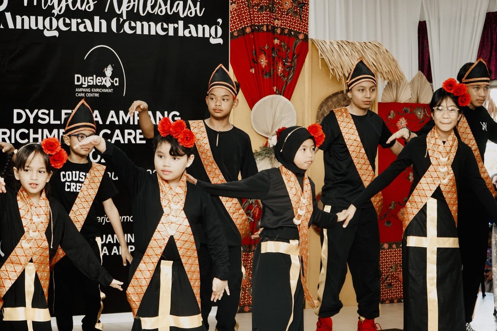 Learners in black and gold traditional costumes dancing on stage